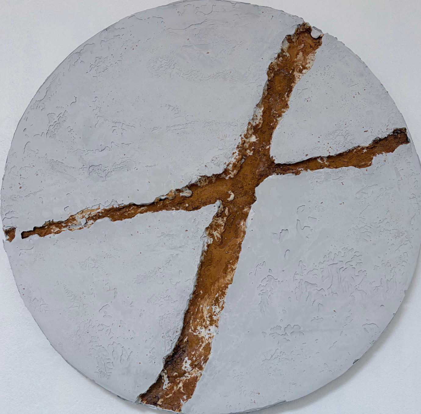 Escultura mural en concreto atravesada por una veta de óxido de hierro